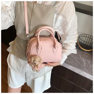 Pink leather bowling bag detail shot featuring twin top handles and cute teddy bear charm.