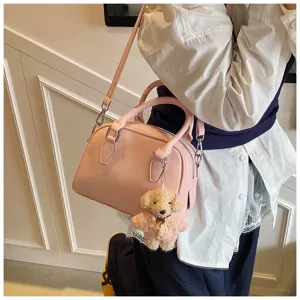 Close-up of a pink soft leather bowling bag with cute teddy bear charm, stylish detail.