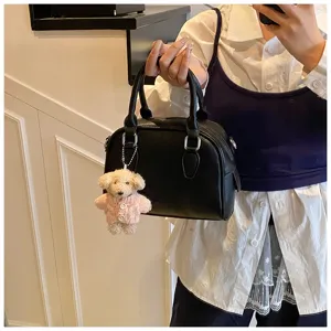 Detailed view of women's black PU leather bowling handbag with cute bear plush keychain accessory.