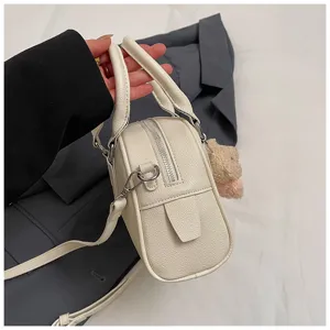 Close-up of white soft leather bowling shoulder bag, side profile with metal hardware detail.