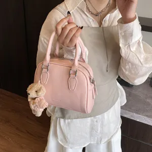 Stylish pink bowling handbag for women, soft leather top-handle shoulder bag with cute bear charm.