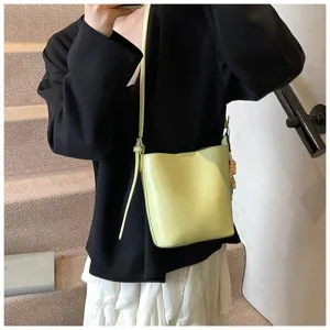 Detail shot of women's glossy bucket bag with shoulder strap and stylish side charm.