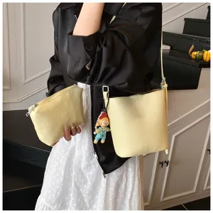 Detail view of stylish yellow bucket bag set with pouch and cute doll pendant, chic commuter wear.