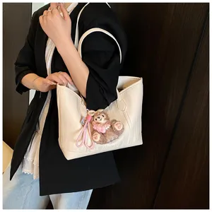 Detailansicht der beigen Soft-Leder-Tragetasche mit einem niedlichen Plueschbaer-Anhaenger.