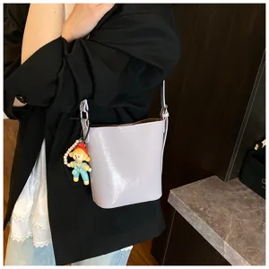 Chic light purple bucket bag with cute doll pendant, stylish shoulder bag for women daily commute.