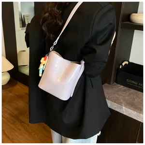 Stylish women's minimalist bucket bag with shoulder strap and charm for daily commute.