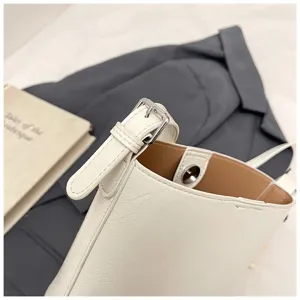 Elegant white bucket bag detail shot with metal buckle and brown lining for women style.