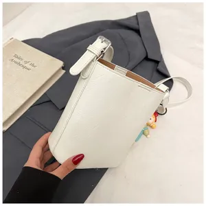 Detailed view of simple white women bucket bag, casual crossbody bag with adjustable shoulder strap.