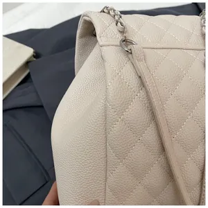 Vue détaillée du sac à dos en cuir matelassé beige avec bandoulière chaîne et texture.