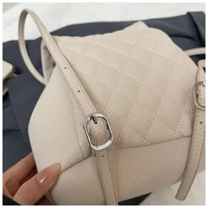 Détail de sac à dos matelassé beige en cuir avec texture grainée et boucle en métal.
