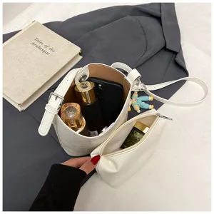 White bucket bag detail shot showcasing spacious interior and matching pouch design for women.