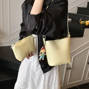 Stylish minimalist yellow leather bucket bag set with pouch and cute doll pendant for women.