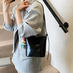 Trendy black patent leather bucket bag for women, chic casual shoulder and cross-body bag.