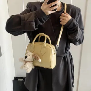 Soft leather bowling bag for women, stylish crossbody handbag with plush dog pendant.