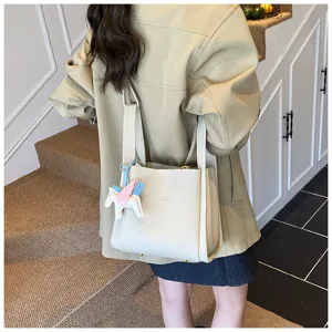 Detail view of a stylish white bucket bag with dual handles and cute pegasus charm.