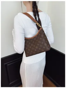 Brown monogram shoulder bag detail view, stylish underarm bag worn by model, chic design.