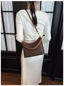 Women fashion monogram shoulder bag detail showcasing brown textured canvas and gold hardware.