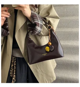 Elegant brown patent leather hobo underarm bag for women, stylish commute shoulder bag with cute charm.