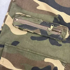 Close-up detail of camouflage cargo shorts fabric and zipper pocket, casual high street style.