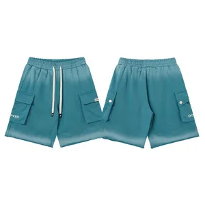 Detail view of gradient wash cargo shorts, featuring multi-pockets, drawstrings, and letters.