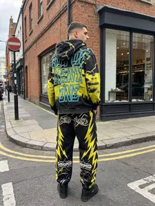 Detailed view of the streetwear black and yellow hoodie and sweatpants set worn outdoors.