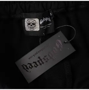 Detailed view of black streetwear pants garment label and hanging tag with logo print.