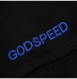 Close-up detail of black denim shorts with blue embroidered letters and fine fabric texture.