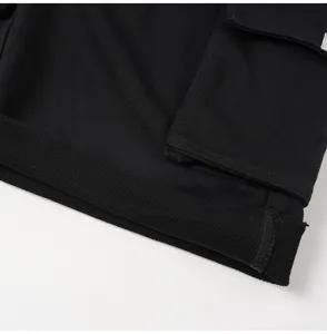 Black cargo shorts detail shot, casual streetwear design with multi pockets and rolled cuff.