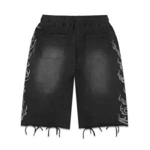 Vue détaillée de shorts streetwear noirs lavés dotés d'imprimés flammes et de franges.