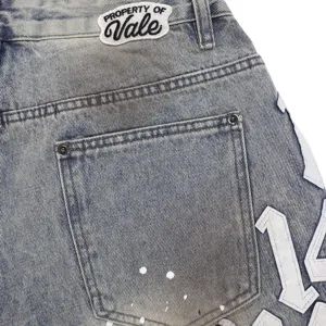 Detailed close-up view of washed denim shorts featuring paint splatter and back brand patch.