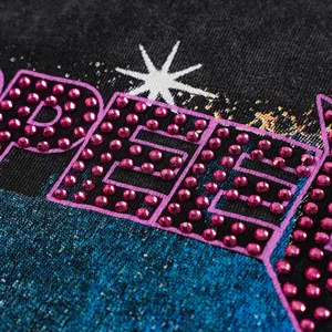 Close-up detail of rhinestone letter graphic on washed distressed black long sleeve t-shirt.