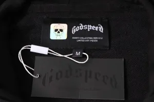 Detailed view of streetwear hoodie neck label and swing tag with skull graphic and branding text.