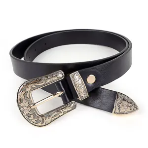 Close-up of vintage metal floral engraved buckle and tip on black PU leather detail.