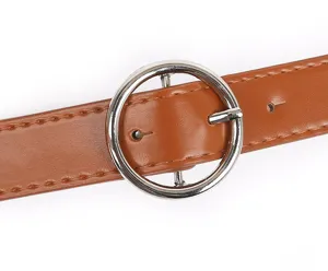 Brown leather belt detail closeup featuring a polished round silver buckle and fine stitching.