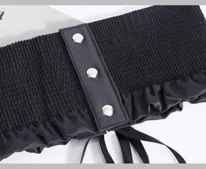 Primer plano de cinturón corsé elástico ancho de mujer con tachuelas metálicas y lazos.