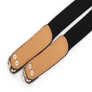 Détail de ceinture élastique noire avec des bouts en simili cuir marron et boucle métallique.