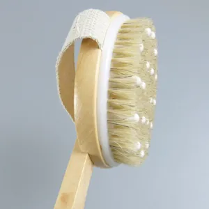 Detailopname van de houten badborstel met zachte haren en massageknoppen met handriem.