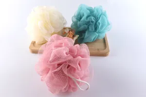 Colorful mesh bath sponges set on wooden tray detail view, soft exfoliating shower puffs.