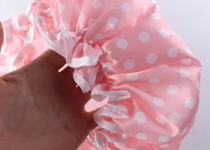 Primo piano dettaglio della cuffia doccia impermeabile a pois rosa con elastico e finitura.