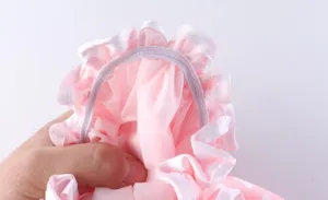 Dettaglio cuffia doccia impermeabile rosa con balze bianche e fascia elastica comoda.