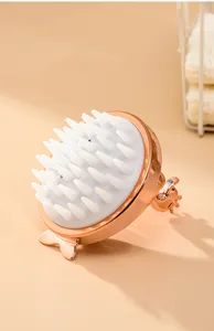 Silicone scalp massage brush detail view showing soft bristles and sleek rose gold finish.