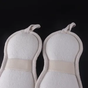 Detail view of white peanut-shaped bath scrubber sponge with elastic hand band and loop.