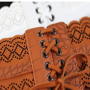 Cintura corsetto larga in ecopelle marrone con motivi traforati e allacciatura frontale.