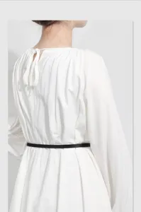Women thin black leather belt styled with white long sleeve dress, elegant waist accessory