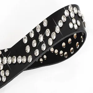 Close up detail view of black leather belt showcasing sparkling rhinestones and metal rivets