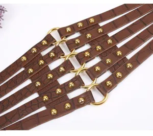 Detailed shot of brown crocodile textured wide waist belt with metallic rings and studs.