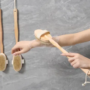 Detail view showing natural wooden long handle bath brush with bristles in use with foam.