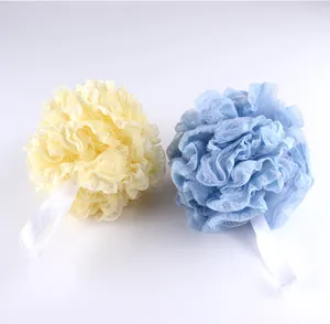 Soft textured ruffle bath sponge close-up, showing delicate mesh net and white hanging ribbon.