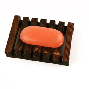Wooden soap dish with slatted drainage design and orange soap bar, perfect for bathroom sink use.