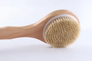 Close-up detail of natural boar bristle bath brush with smooth wooden handle for skin care.